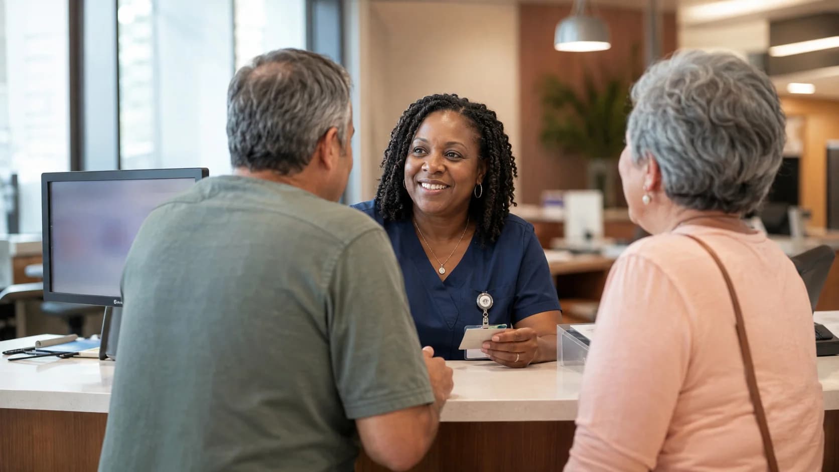 Patient-access coordinator warmly helping a patient and caregiver